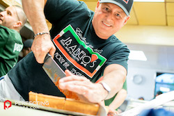 a photo of tony troiano cutting a pizza