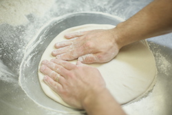 pizza dough being stretched out