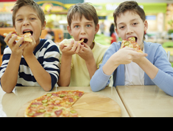 A photo of three kids eating pizza