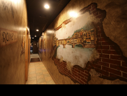 Hallway in a pizzeria with Italian murals of a bridge painted on the wall
