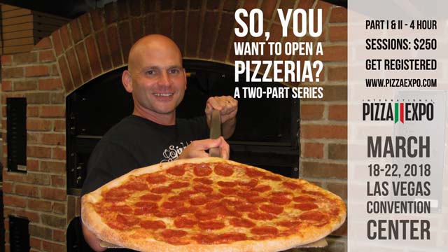 Guy holding a pizza in front of an oven smiling at camera
