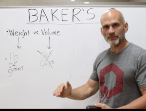Michael Shepherd standing in front of a white board explaining Baker's Percent