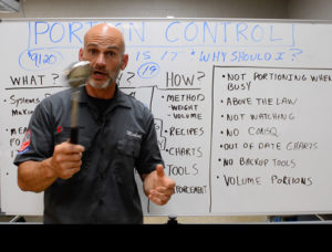 Michael Shepherd standing in front of a whiteboard holding a spoodle discussing portion control methods