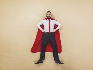 A man wearing a cape stnading in a superhero pose